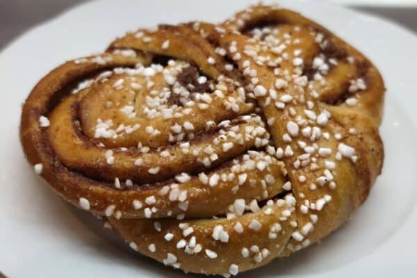 Twisted cinnamon bun with pearl sugar on a white plate
